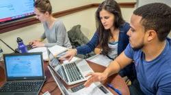 3 students at table working on a collaborative presentation